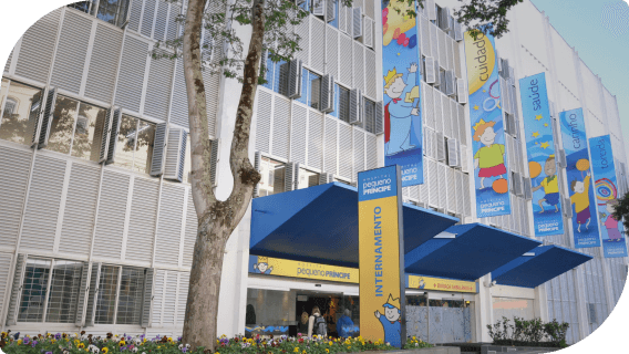 Hospital Pequeno Principe, possui estrutura de predio da cor branca, com 1 puxado na entrada na azul e placas de identificação do hospital