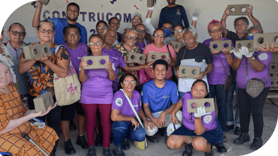 Instituto Iteva do idoso, imagem composta por pessoas segurando um bloco de cimento retangular com 2 buracos redondondos abertos em cada ponta