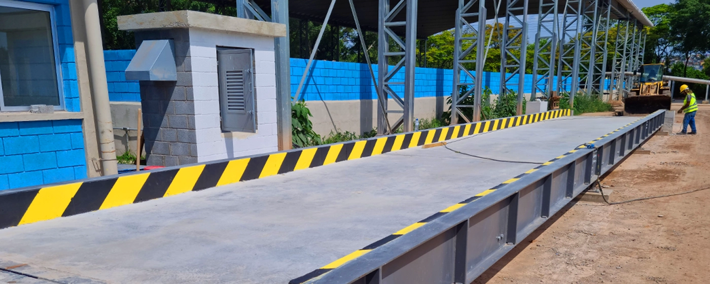 Funcionário com macacão azul, capacete epi branco, óculos de proteção preto, fazendo manutenção em 1 máquina em ambiente industrial